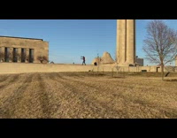 Man red jacket wall dead grass arms out circle