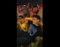 Guy crowdsurfs on an inflatable lemon slice at outdoor EDM concert