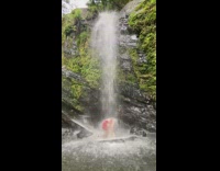 Woman in dress slips on the rock of the waterfalls