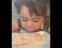 Kid eating corn with cheese all over her face 