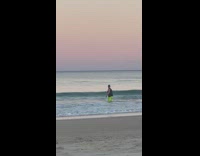 Man in black tank top films beach waves