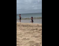 Boy takes picture of mother at beach