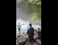 Woman spread arms pose front of falls