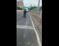 2 guys drive mobility scooters on road 