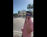 Guy at intersection catch grape thrown from building above with mouth