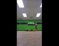 Girl tries to front flip her friend by holding onto her hand between legs, friend face plants into floor hard green room