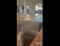 Car dealership employee drives over curb with new car