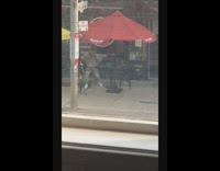 Girl sits table red umbrella phone tripod