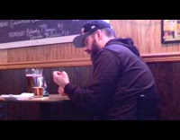 Guy talks to phone beer pitcher bar 