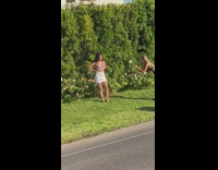 Lady in white skirt poses with garden hedge 