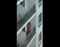 Girl wearing orange bikini poses on balcony 