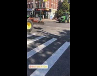 Two tractors driving down the street