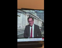 Woman in red top poses behind the news reporter on TV Part 4