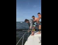 Guy gets pushed off boat  and get foot and legs caught on rail, bends it the wrong way and hangs off side of boat