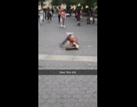 Collab Subway Creatures - Woman in orange bra and underwear with white bra tied around face dances crazy with toy infant baby on the ground at park