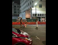Woman in black crop top and white pants bend in the middle of the street