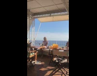 Woman in violet dress poses with a selfie stick on the couch