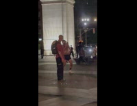 Shirtless guy walks around park with bag over himself 