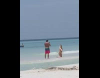 Lady in white bikini poses on beach shore