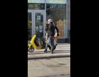 Guy with lots of fake animal tails smoking cigarette on sidewalk