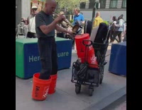 Performer playing trumpet with one hand and buckets on feet