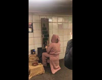 Musician pink clothing plays drums on glass bottles in subway station