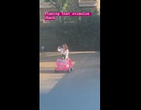 White shirt girl drives pink toy car 