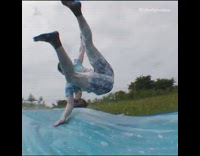 Guy slides off ramp on soap water slide with friends