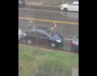 Guy washes blue car in rain 