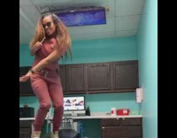 Pediatric dentist in red scrubs dances to Beyonce on patients chair using toothbrush as microphone