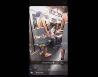 Two guys wear gray trash cans over bodies and play the drums on them, freestyle rap on subway 