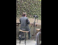 Man black jacket sip mug tripod camera