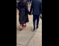 Couple walking on sidewalk with woman wearing mans shoes 