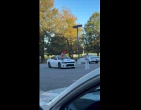 Man clown costume poses on car hood