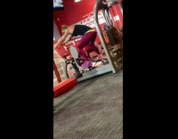 Woman pink leggings uses thigh workout machine the opposite way at the gym