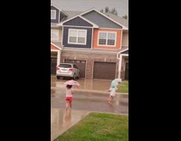 Two girls with umbrella play in rain