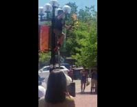 Man juggling flaming torches on tall unicycle