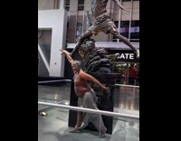 Homeless man jumps glass and poses with statue