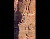 Girl sits shoulders guy stands cliff edge 
