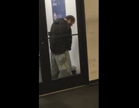 Balding guy black sweater peeing into trashcan