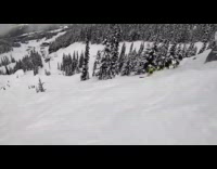 Two skiers jump off tall ledge next to ski lift