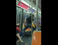 Man with brown brim hat stands with legs spread out on subway train