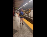 Woman carry sousaphone and bucket subway station