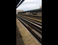 Guy standing on train platform with huge big  flag