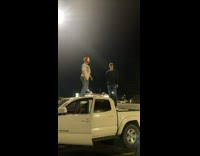Two guys dance on top of parked truck 