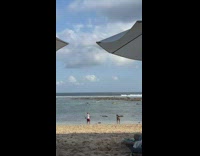 Woman in cyan bikini dances to the music at the beach