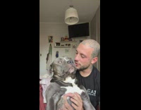 Guy sing while holding large pet dog. 