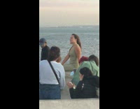 Woman green jumpsuit sit on ledge ocean