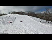 Boy slides down snowy slope very fast and loses his sled down the hill
