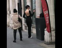 Woman backless top poses with a coffee on the sidewalk